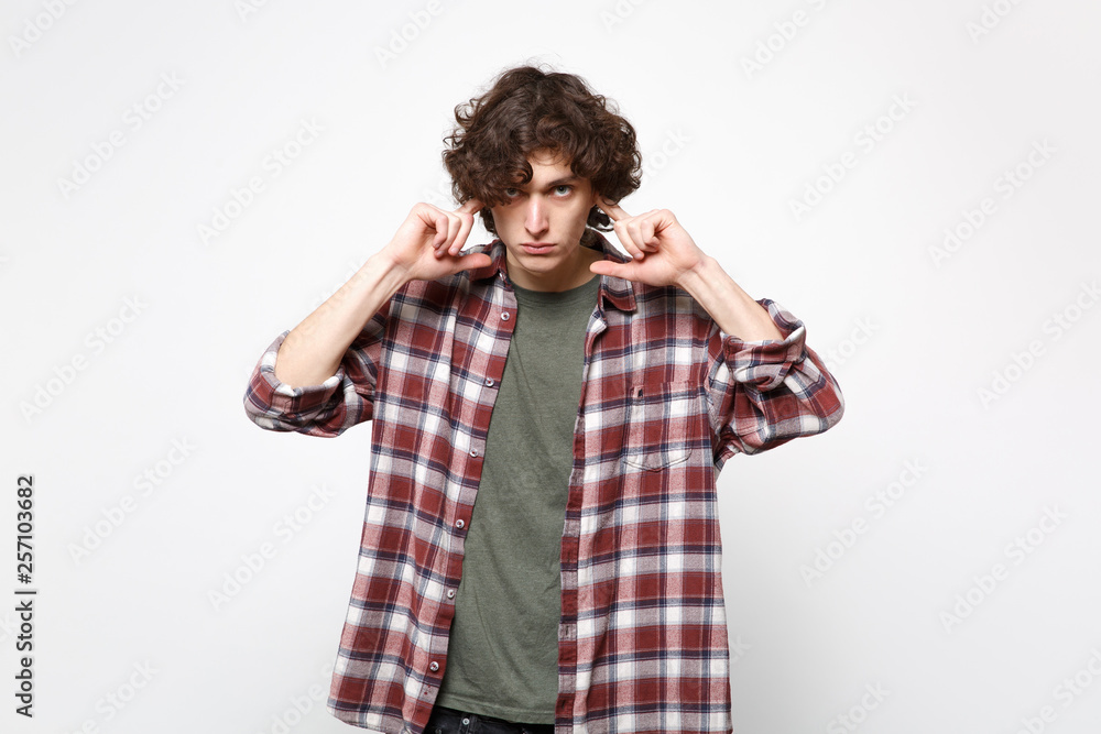 Portrait of concerned young man in casual clothes looking camera covering ears with fingers isolated on white wall background in studio. People sincere emotions, lifestyle concept. Mock up copy space. Portrait of concerned young man in casual clothes looking camera covering ears with fingers isolated on white wall background in studio. People sincere emotions, lifestyle concept. Mock up copy space.
