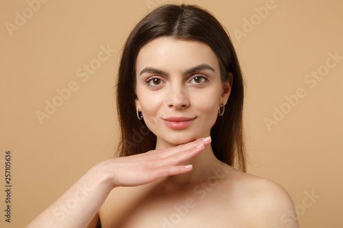 Close up brunette half naked woman 20s with perfect skin, nude make up isolated on beige pastel wall background, studio portrait. Skin care healthcare cosmetic procedures concept. Mock up copy space.