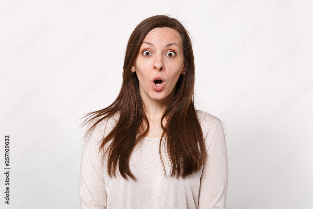 Portrait of shocked amazed pretty young woman in light clothes looking camera, keeping mouth open isolated on white background in studio. People sincere emotions lifestyle concept. Mock up copy space. Portrait of shocked amazed pretty young woman in light clothes looking camera, keeping mouth open isolated on white background in studio. People sincere emotions lifestyle concept. Mock up copy space.