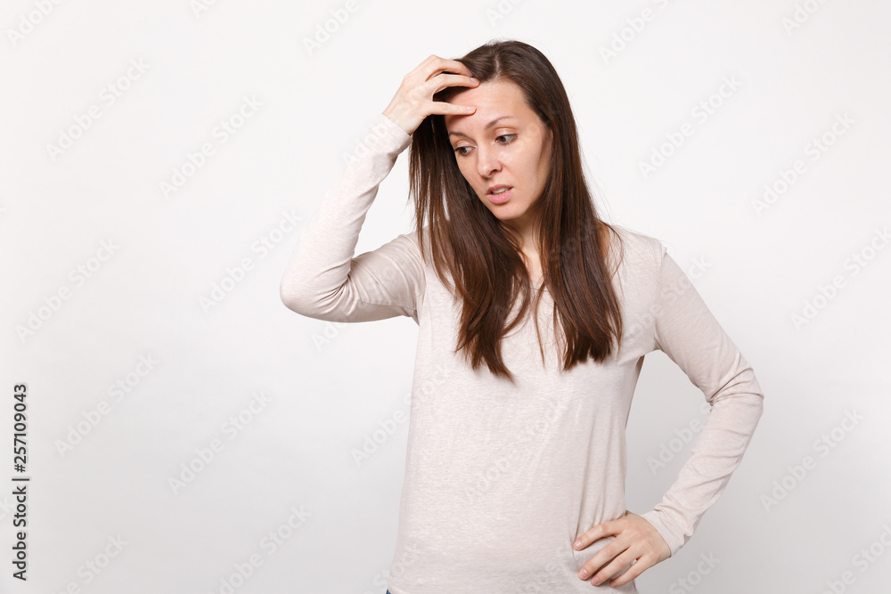 Portrait of preoccupied young woman in light clothes looking down, putting hand on head isolated on white wall background in studio. People sincere emotions, lifestyle concept. Mock up copy space. Portrait of preoccupied young woman in light clothes looking down, putting hand on head isolated on white wall background in studio. People sincere emotions, lifestyle concept. Mock up copy space.