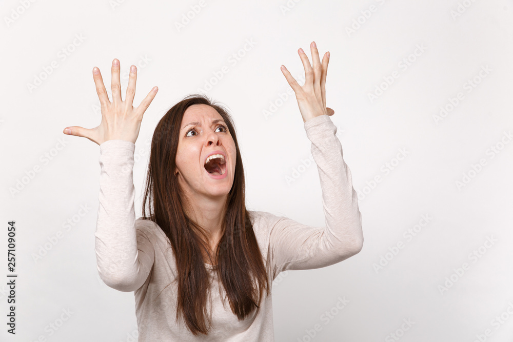 Portrait of screaming young woman in light clothes looking up aside rising, spreading hands isolated on white wall background in studio. People sincere emotions, lifestyle concept. Mock up copy space. Portrait of screaming young woman in light clothes looking up aside rising, spreading hands isolated on white wall background in studio. People sincere emotions, lifestyle concept. Mock up copy space.