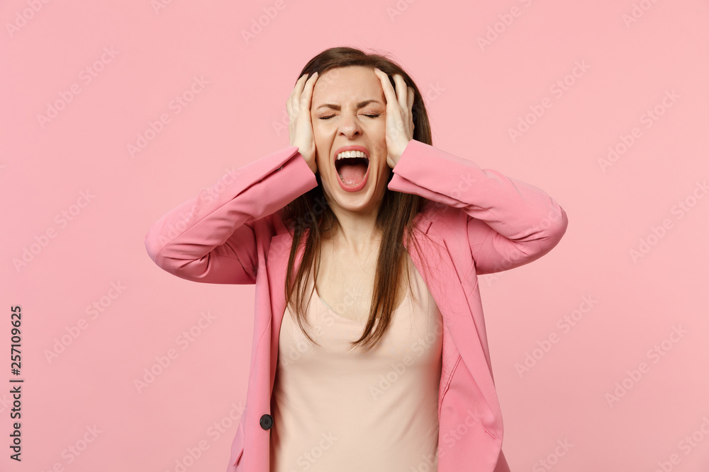 Screaming young woman wearing jacket keeping eyes closed and putting hands on head isolated on pastel pink wall background in studio. People sincere emotions, lifestyle concept. Mock up copy space. Screaming young woman wearing jacket keeping eyes closed and putting hands on head isolated on pastel pink wall background in studio. People sincere emotions, lifestyle concept. Mock up copy space.
