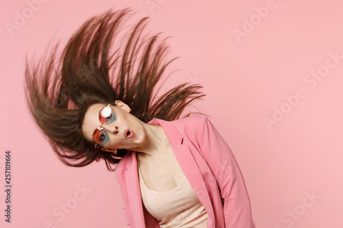 Принти на полотні Portrait of cheerful amazed young woman in heart glasses jumping with fluttering hair isolated on pastel pink wall background in studio