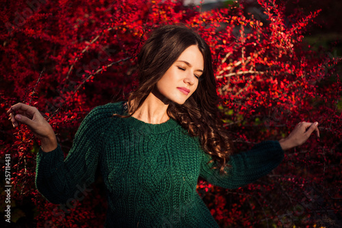 Beautiful woman posing on red tree leaf background.