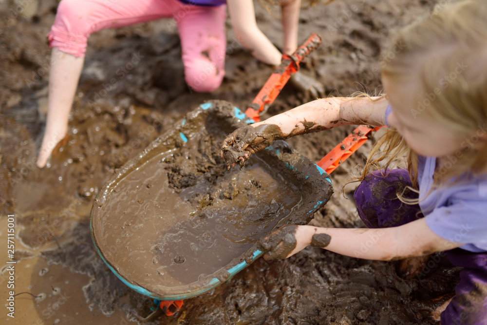 Two funny little girls playing in a large wet mud puddle on sunny summer  day. Children getting dirty while digging in muddy soil. Stock Photo |  Adobe Stock
