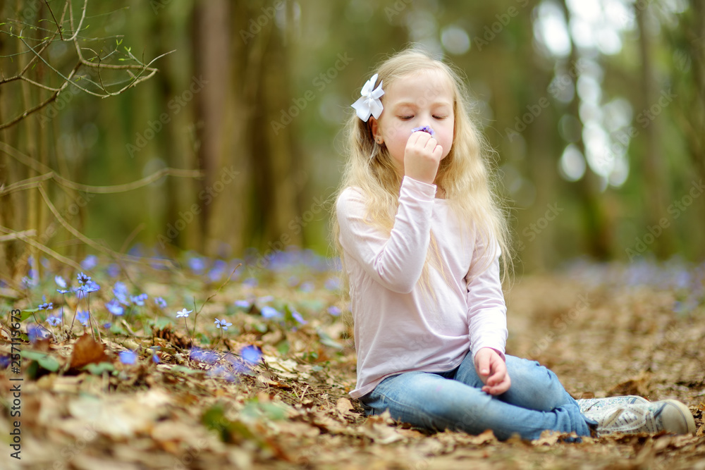 Adorable little girl picking the first flowers of spring in the woods on beautiful sunny spring day. Adorable little girl picking the first flowers of spring in the woods on beautiful sunny spring day.