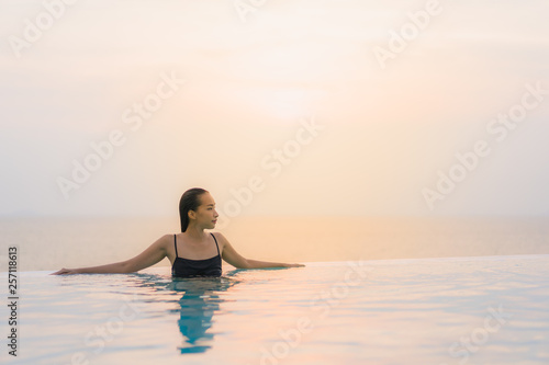 Portrait beautiful young asian woman happy smile relax around swimming pool in hotel resort