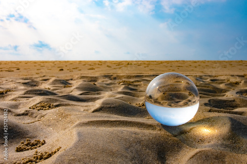 Glass balls show through crystal clear on the beach, sea, clouds, blue sky in the summer background. Text entry area, yes on the business travel website