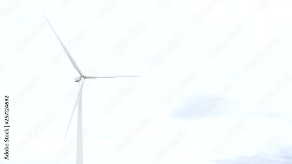 Single wind turbine spinning against a white sky Single wind turbine spinning against a white sky