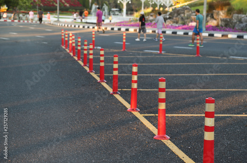 Closeup of traffic regulation pole and rumble strip on asphalt road in public park in sunny evening. 