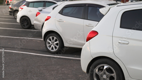 Closeup of rear or back side of white car with other cars parking in parking area in twilight evening. © Amphon