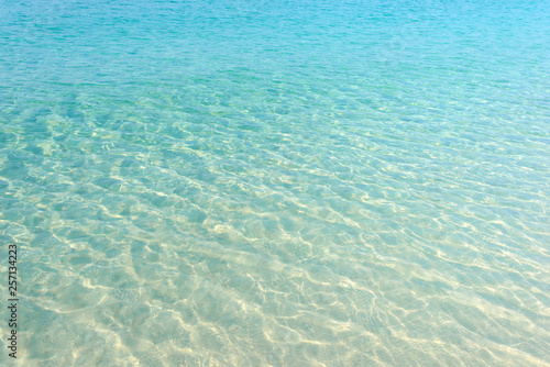 Clear blue water ripple on sandy beach. Sea water reflections surface. Tropical sunny summer day.