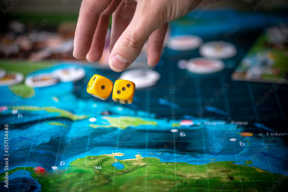 The hand throws two yellow dice on the playing field. Gaming moments in dynamics. Concept Board games strategy The hand throws two yellow dice on the playing field. Gaming moments in dynamics. Concept Board games strategy