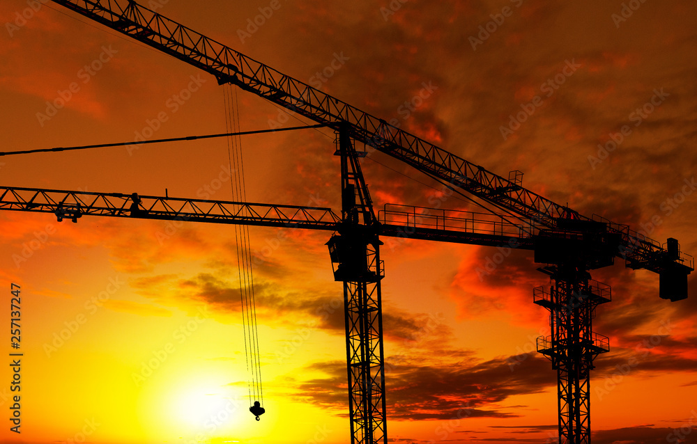 Silhouette of crane construction building towers at sunset
