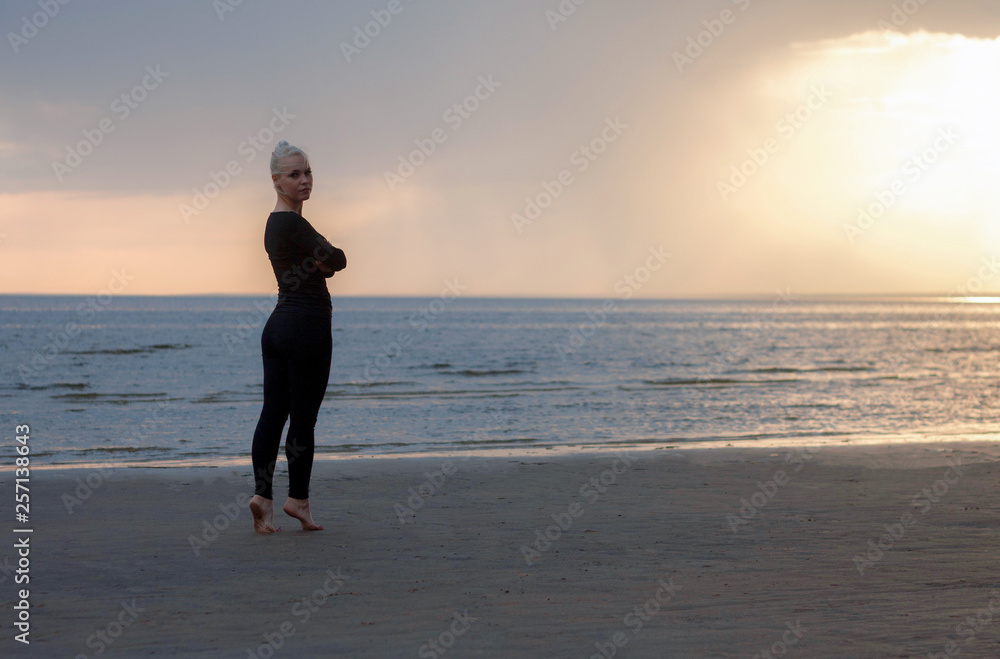 girl in black on tiptoes, sunset on the beach