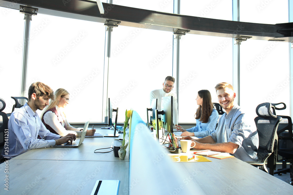 Obraz premium Young modern colleagues in smart casual wear working together while spending time in the creative office.