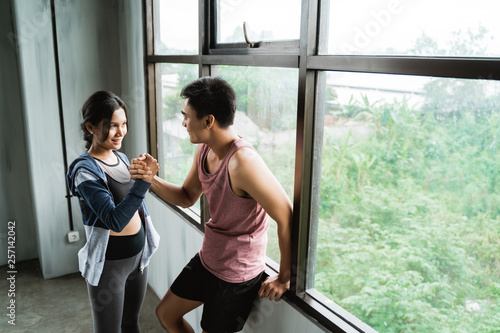 sportsman and sportswoman resting beside windows after training session at the gym © Odua Images