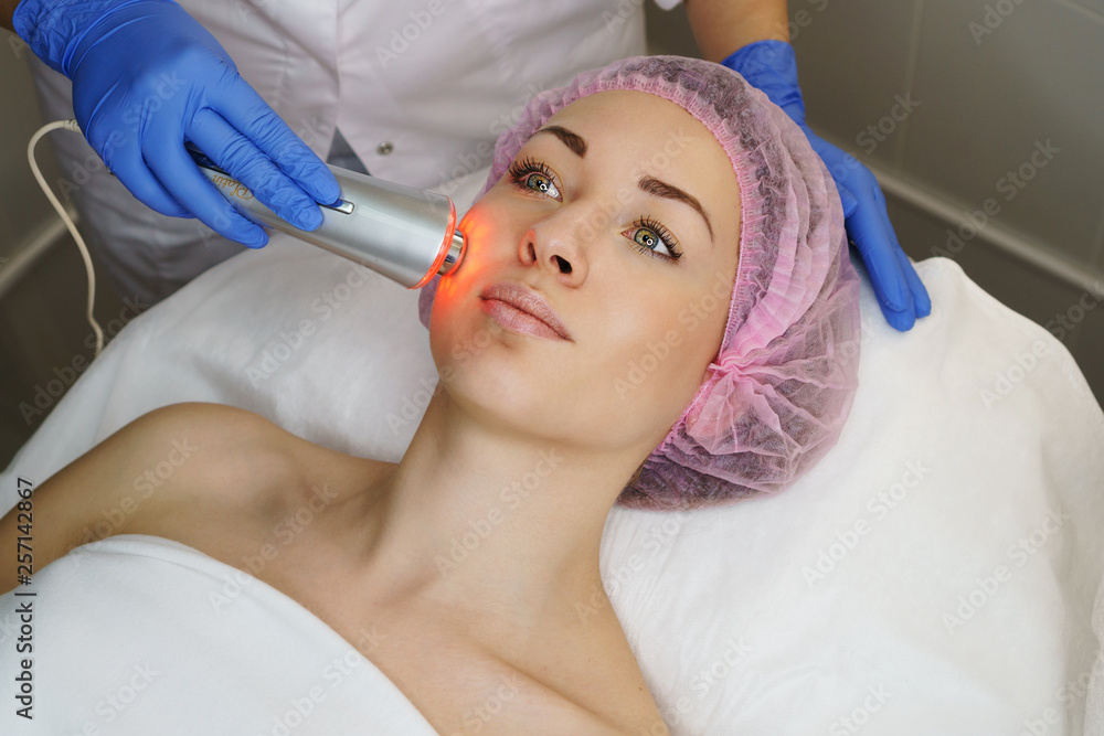 Hardware cosmetology. Ultrasound chromotherapy. Beautician carries out procedure for tightening skin of face. Spa. Non-surgical cosmetology. Skin peeling