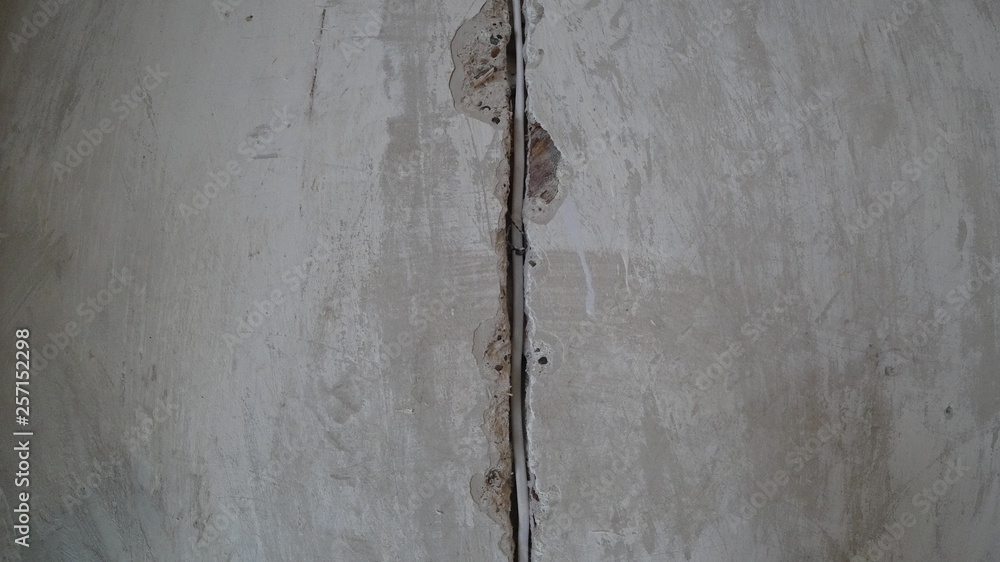 Background concrete wall divides in the middle of the groove with an electric wire, the concrete wall is gray, shabby Background concrete wall divides in the middle of the groove with an electric wire, the concrete wall is gray, shabby