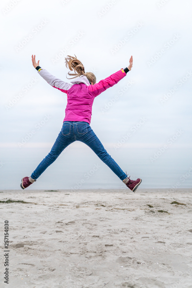 jundes Mädchen springt am Strand vor Freude in die Luft jundes Mädchen springt am Strand vor Freude in die Luft