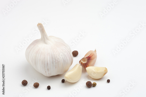Image of fresh garlic head with black pepper grains isolated on white background. Vegetables. Spices and seasonings. Food. Studio photo.
