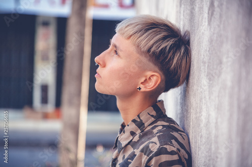 Fotografie Stylish brutal young woman with short hair and shaved temples with a smartphone