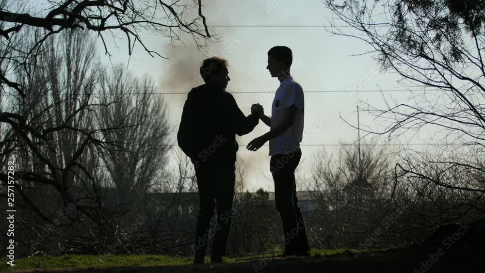 Silhouette of two young scared men that saw black smoke in the sky from burning houses Silhouette of two young scared men that saw black smoke in the sky from burning houses