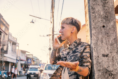 Fotografie Stylish brutal young woman with short hair and shaved temples with a smartphone