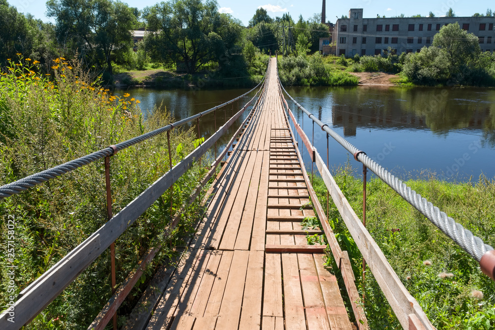 Suspension bridge over the river Msta on a summer day. City Borovichi, Russia