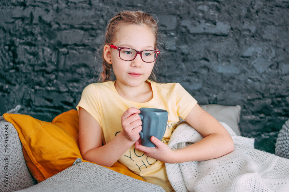 Cute tween girl in yellow t-shirt with cup of tes in bed, cozy home