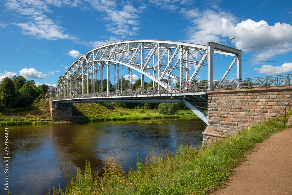 Borovichi, Russia - August 8, 2018: First in Russia steel arch bridge on river Msta in sunny summer day. Novgorod region, Borovichi, Russia. Was built in 1905. Borovichi, Russia - August 8, 2018: First in Russia steel arch bridge on river Msta in sunny summer day. Novgorod region, Borovichi, Russia. Was built in 1905.