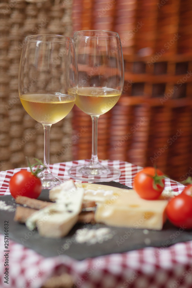 Romantic dinner for a couple on Saint Valentine's day: two glasses of cold white wine and gourmet french cheese plate with bread and fresh tomatoes. Nicely served on a red and white napkin