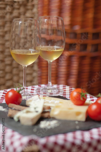 Romantic dinner for a couple on Saint Valentine's day: two glasses of cold white wine and gourmet french cheese plate with bread and fresh tomatoes. Nicely served on a red and white napkin