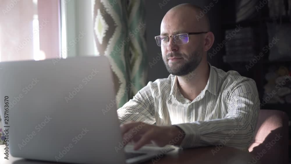 Young man in glasses communicates in a social network and smiles. Young man in glasses communicates in a social network and smiles.