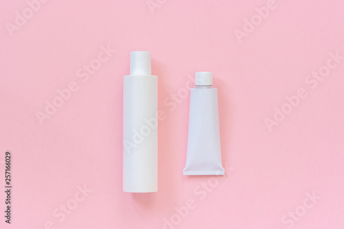 Blank cosmetic or medical white plastic bottle and tin tube for cream, shampoo, ointment, toothpaste or other product on pink background. Template or Mock up for your design. Copy space Top view