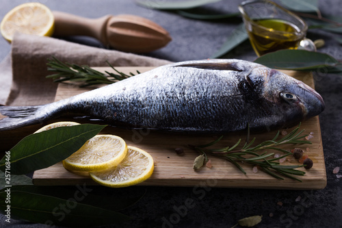 Mediterranean seafood concept. Raw dorado fish with olive oil, lemon, rosemary on stone table. Fresh organic sea bream or dorada fish. Top view dorado fish