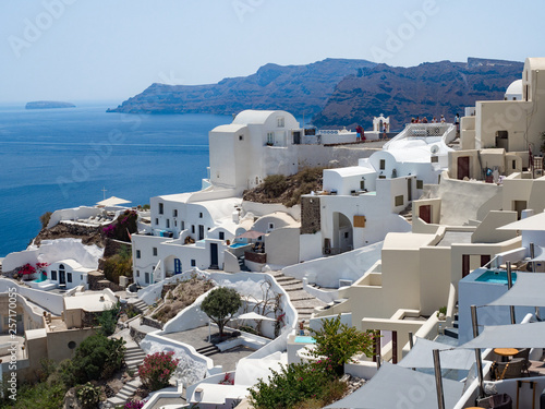 Greece, July, 2018: Oia town on Santorini island. Traditional and famous houses and churches with blue domes over the Caldera, Aegean sea