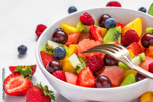 fruit salad with watermelon  strawberry  cherry  blueberry  kiwi  raspberry and peaches in a bowl with fork