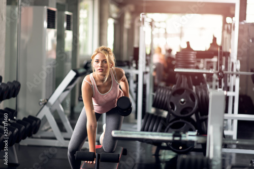 Strong woman doing exercises with dumbbells in gym