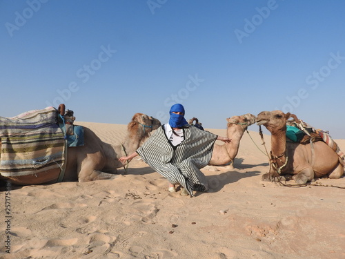 the woman in the turban  the face is closed  with a camel in the Sahara desert.