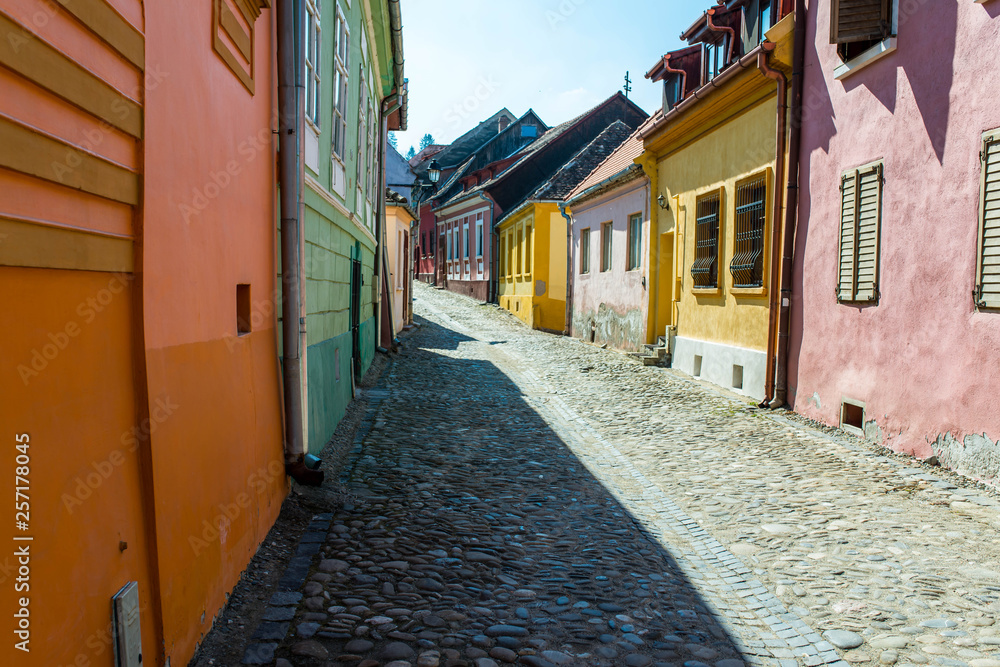 Colorful narrow medieval street on a bright spring day in Sighisoara, Romania.