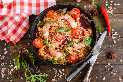 Tasty pasta with shrimp and tomato on a frying pan