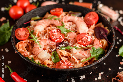 Tasty pasta with shrimp and tomato on a frying pan