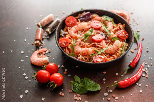 Tasty pasta with shrimp and tomato on a frying pan