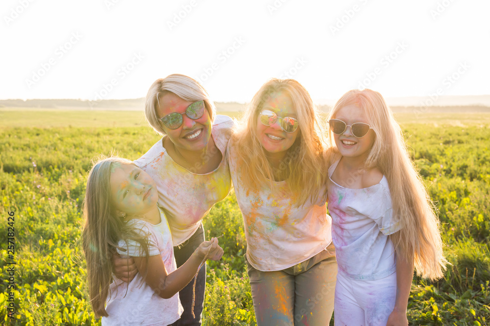 Festival of holi, friendship, happiness and holidays concept - little girls and women in glasses hugging on the festival of Holi. Festival of holi, friendship, happiness and holidays concept - little girls and women in glasses hugging on the festival of Holi.