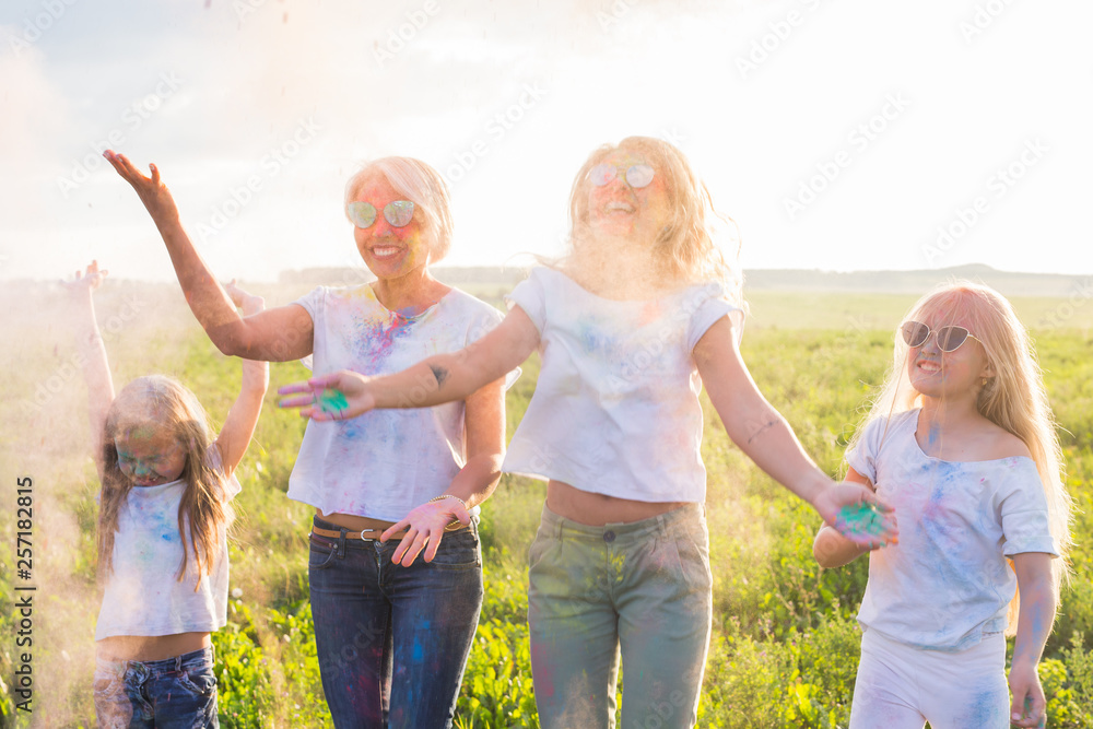 Fototapeta premium Friendship, Indian holidays and people concept - young women and children dancing on the summer field on festival of holi