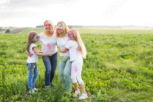 Friendship, Indian holidays and people concept - young women and children dancing on the summer field on festival of holi