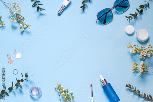 Beauty concept frame on the blue background with spring flowers. Cosmetics top view. Copy space