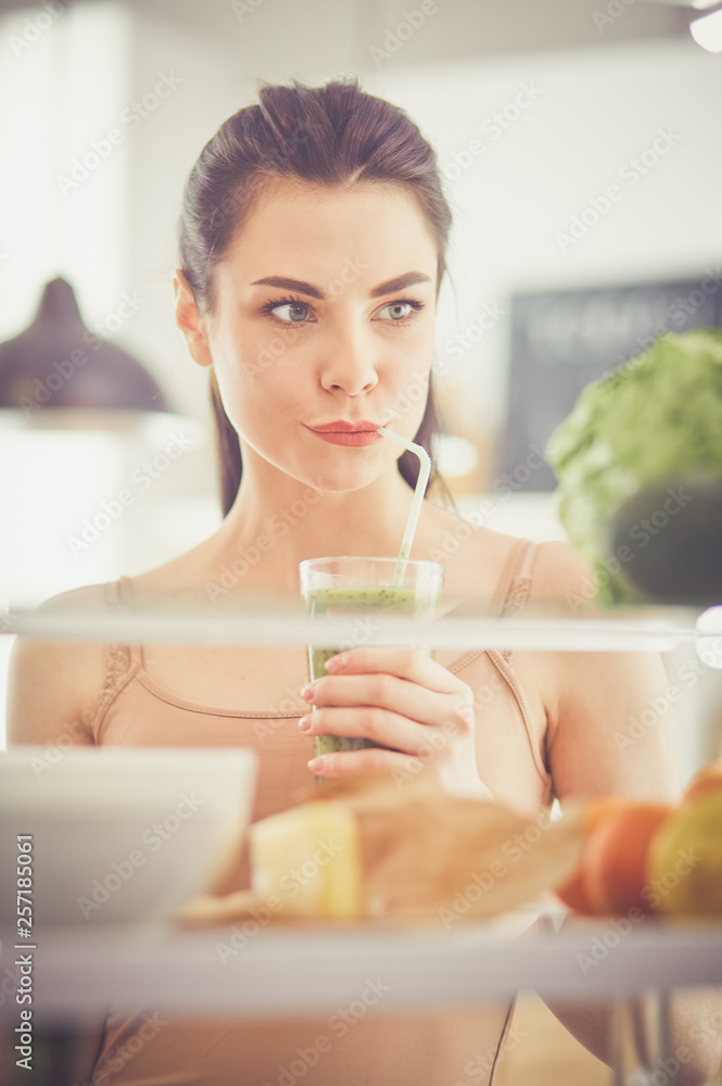 Smiling woman taking a fresh vegetable out of the fridge, healthy food concept Smiling woman taking a fresh vegetable out of the fridge, healthy food concept