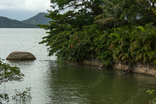 Small isolated stone at the end of a river entering the sea in Paraty, Brazil. photo